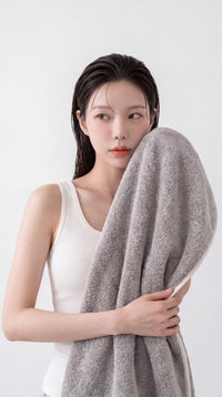 Woman gently patting her face dry with the soft gray Somara charcoal bamboo towel after skincare